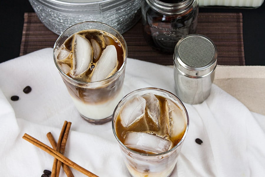 Iced Cinnamon Macchiato on a white cloth with cinnamon sticks garnish