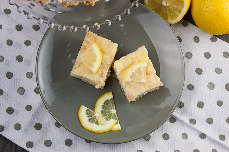 Lemon Cheesecake Shortbread Bars on a gray plate garnished with lemon slices