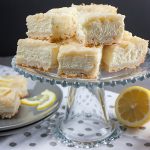 Lemon Cheesecake Shortbread Bars on a glass serving pedestal.