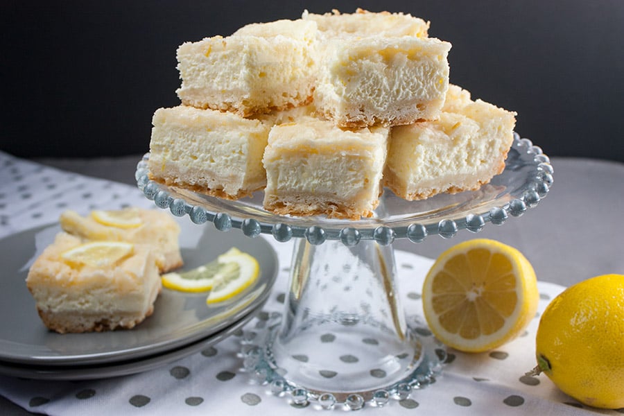 Lemon Cheesecake Shortbread Bars on a glass serving pedestal.