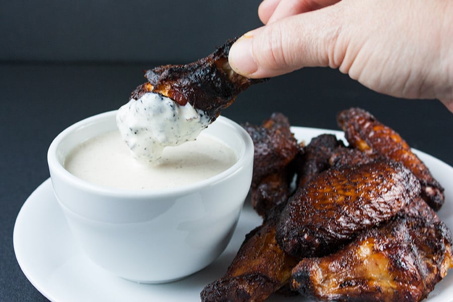 Alabama White BBQ Sauce being used on a smoked chicken wing.