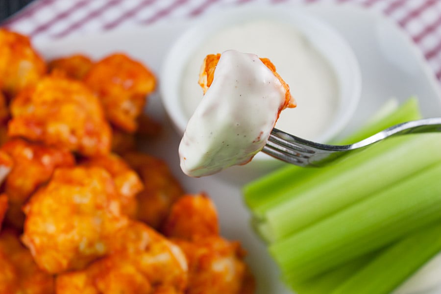 One piece of baked cauliflower bite on a fork dipped in ranch.
