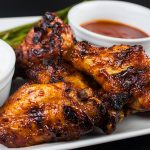 Cajun Smoked Wings with two sauces on a white plate.