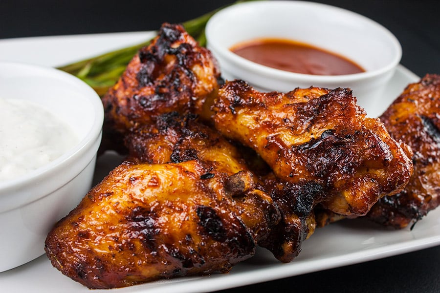 Cajun Smoked Wings with two sauces on a white plate.