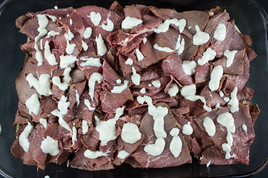 Roast beef layered on the bottom buns drizzled with horseradish sauce.