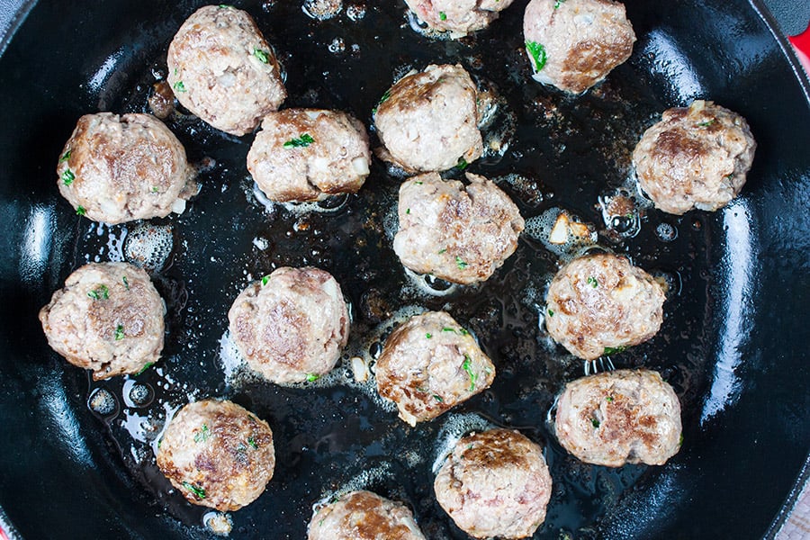 Swedish meatballs browning in a cast iron skillet