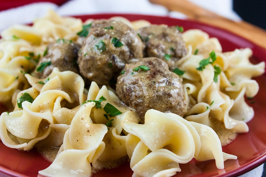 Swedish Meatballs over egg noodles on a red plate