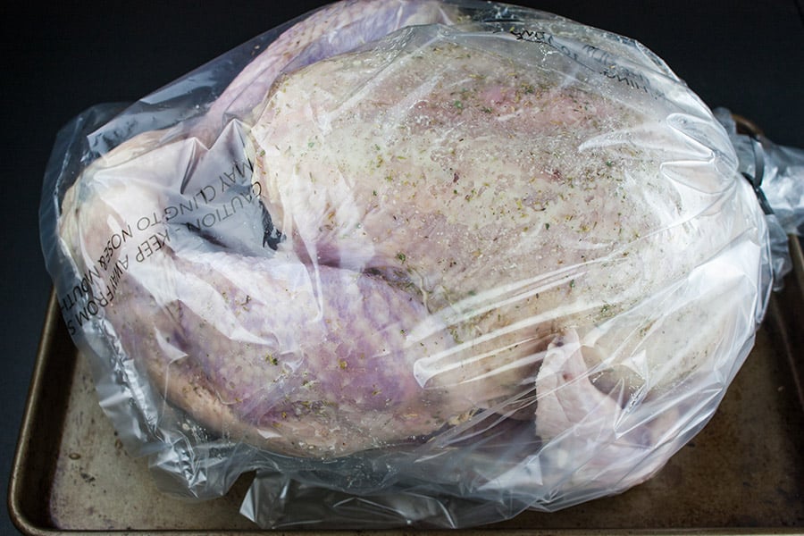 Simple Succulent Roast Turkey (Dry Brine) - turkey rubbed with brine and placed in a plastic bag on a rimmed baking sheet