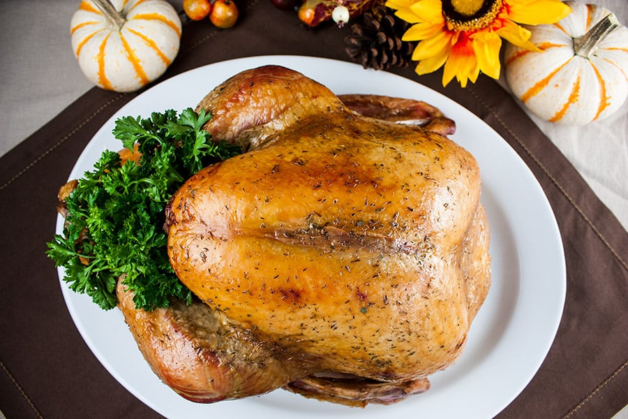 Simple Succulent Roast Turkey (Dry Brine) - cooked turkey on a white platter garnished with parsley