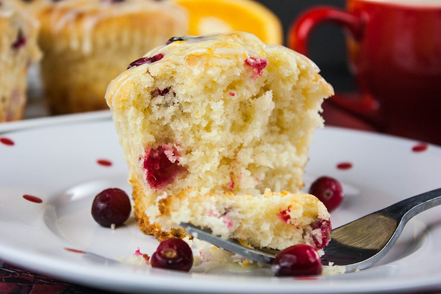 Cranberry orange muffins cut open on a white plate with red dots.