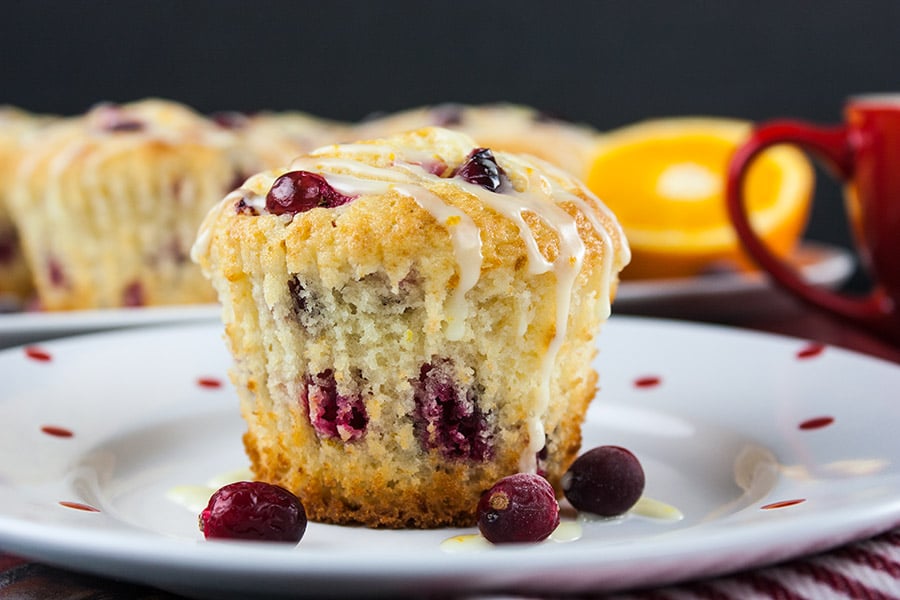 Cranberry orange muffins on a white plate with red dots.