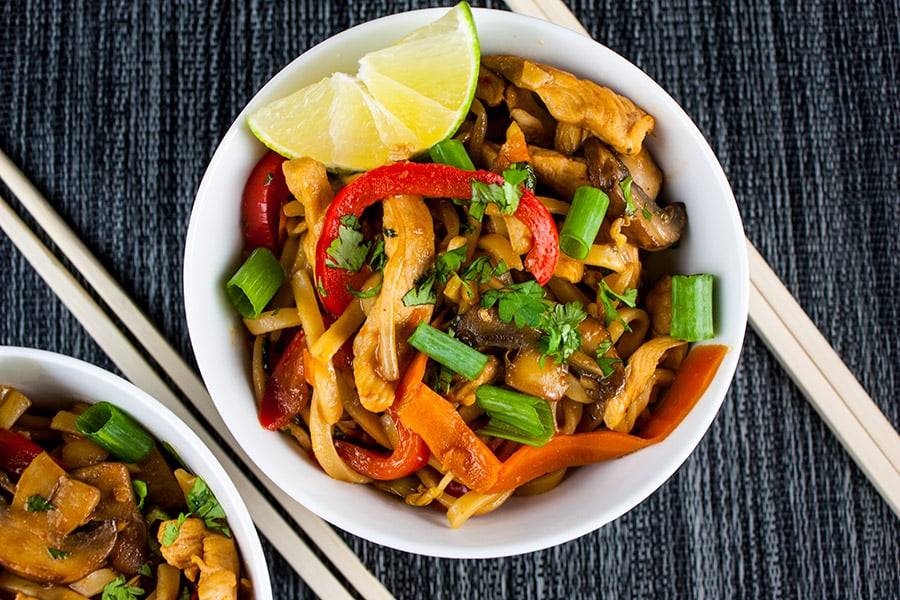 Spicy Thai Chicken Noodle Bowl garnished with a lime wedge.