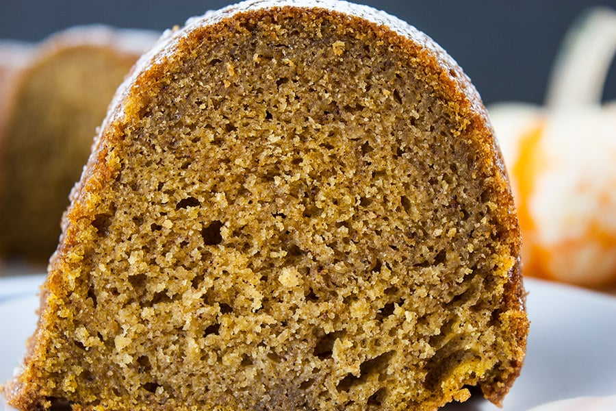 A close up of a slice of pumpkin spice bundt cake on a white plate.