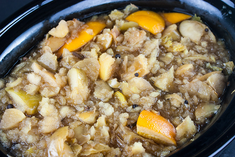 Ingredients for apple cider cooked in the crock of a slow cooker.