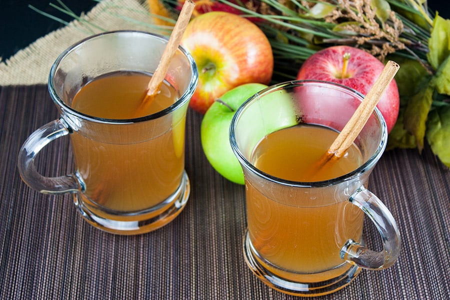 Slow Cooker Apple Cider in two glass mugs with cinnamon stick garnish