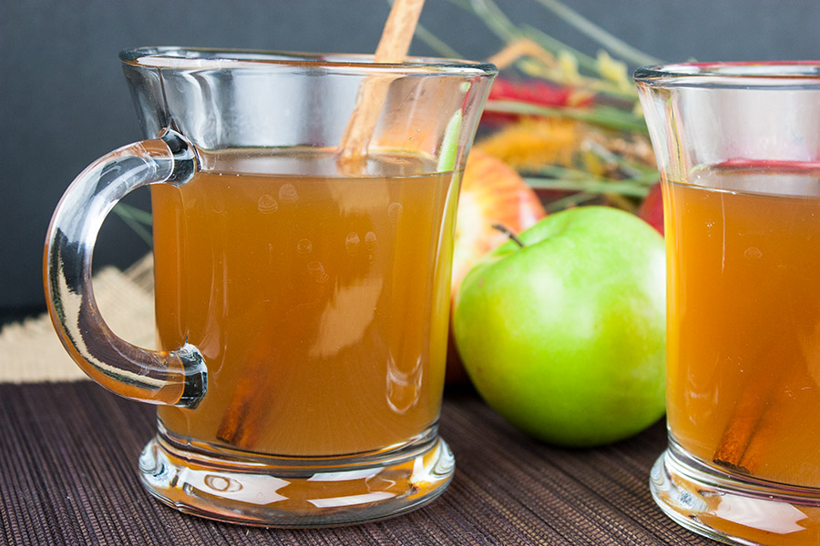 Slow Cooker Apple Cider in two glass mugs with cinnamon stick garnish.