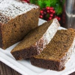 Spicy Gingerbread Loaf on a white plate with a couple of slices laying over.