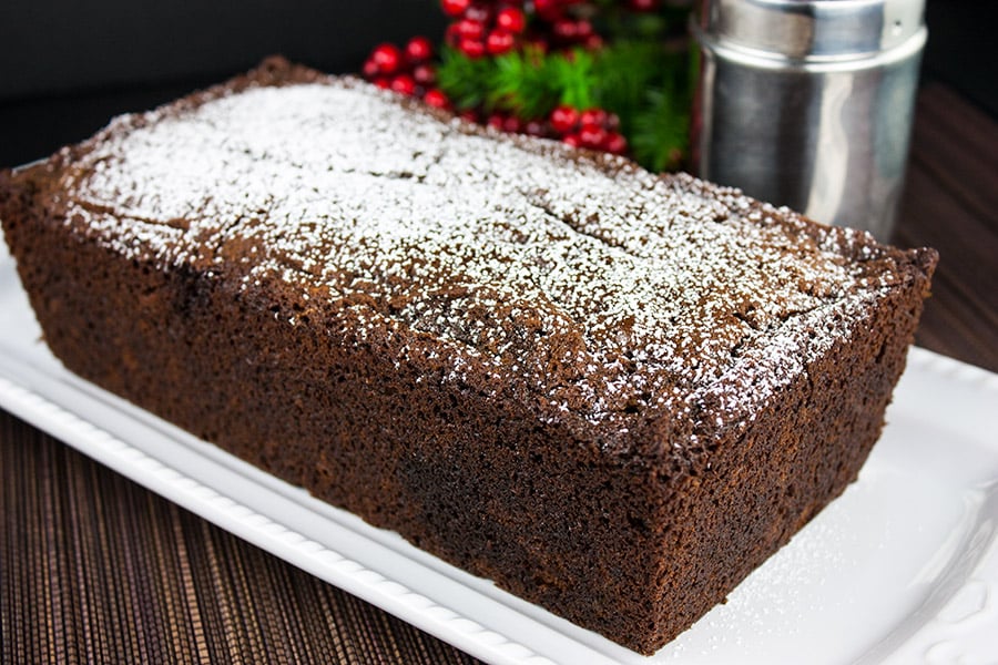 Spicy Gingerbread Loaf on a white platter garnished with powdered sugar.