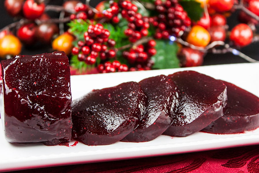 Cranberry sauce sliced on a white tray with berries in the background.