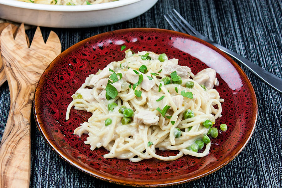 Turkey tetrazzini on a red plate garnished with chopped parsley.