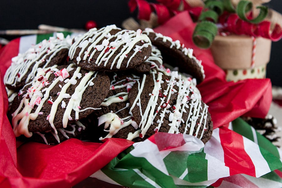 Chocolate Peppermint Cookies stacked in tin with red, white and green tissue paper.