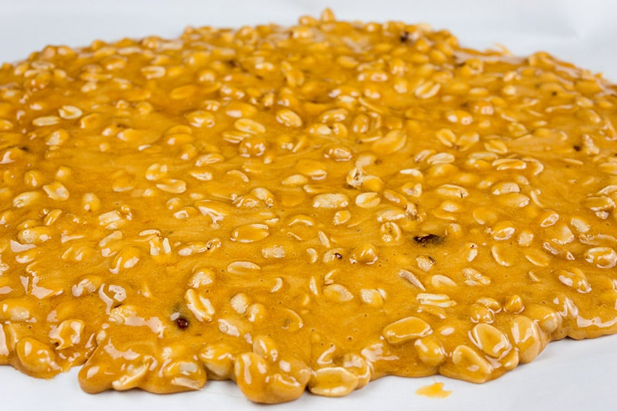 Old-Fashioned Peanut Brittle spread out to cool on parchment paper.