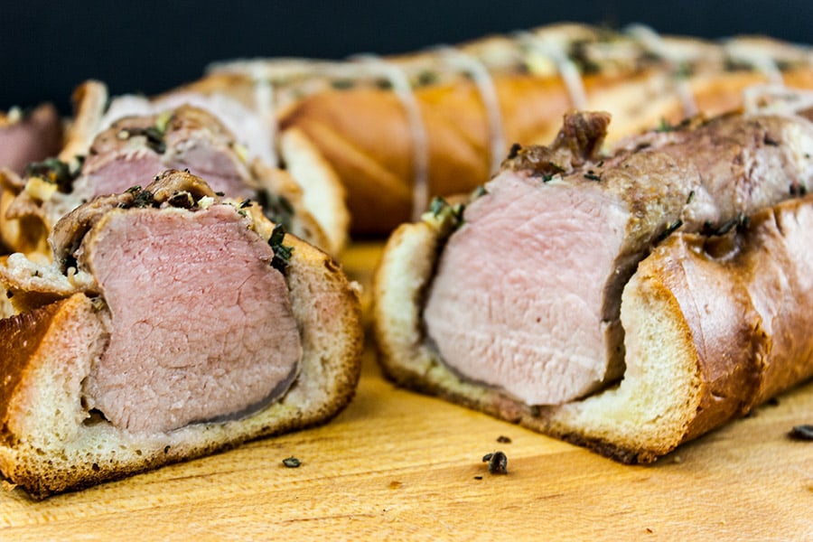 Tuscan pork tenderloin sliced on wooden cutting board.