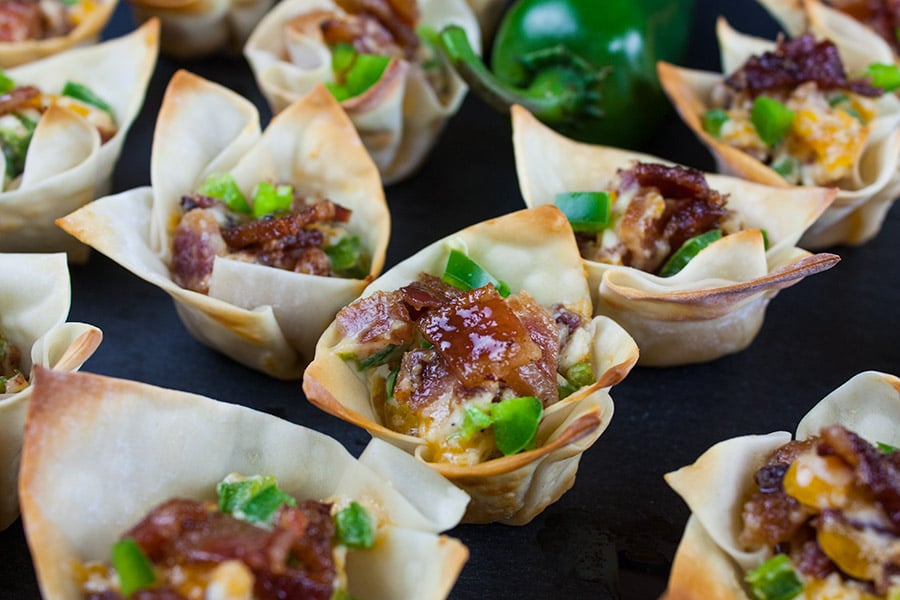 Candied Bacon Jalapeno Poppers lined up on a dark surface.