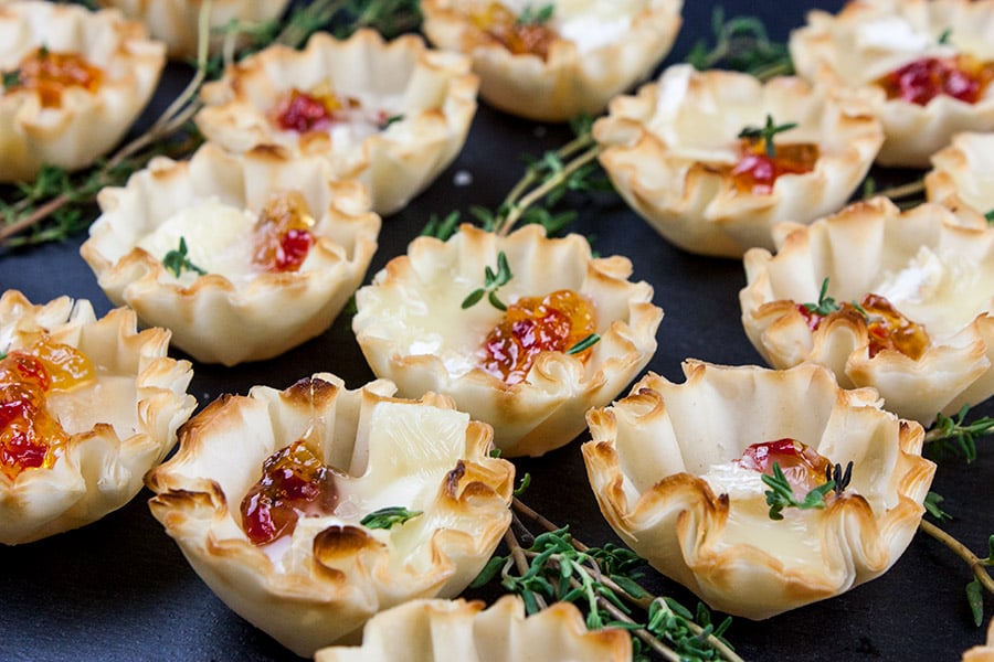 close up of Pepper Jelly Brie Bites on a black slate garnished with fresh thyme