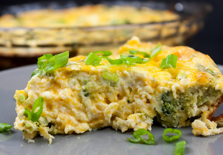 slice of crustless broccoli cheddar quiche on gray plate garnished with diced green onions