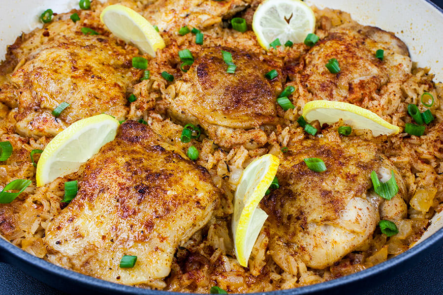 One Pan Spanish Chicken and Rice garnished with lemon slices and chopped green onions.