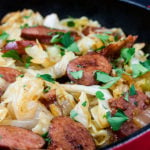 Fried cabbage and sausage in a skillet.