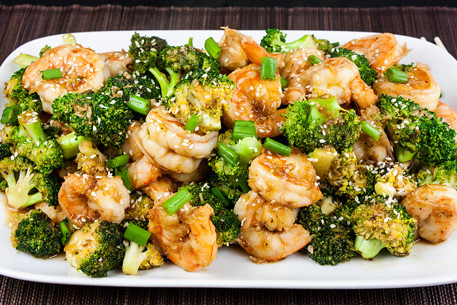 Shrimp and Broccoli Stir Fry  on a white platter garnished with sesame seeds and green onions