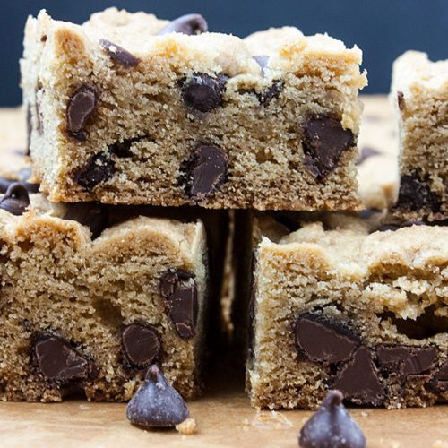 Chocolate chip bars stacked on a wooden cutting board.