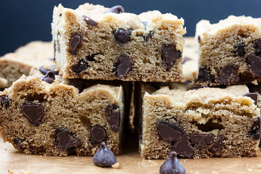 Chocolate chip bars stacked on a wooden cutting board.