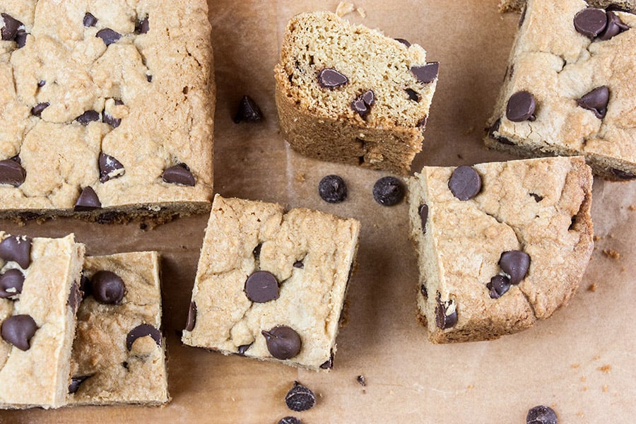 Chocolate chip cookie bars cut into pieces on a wooden board.