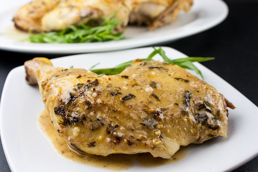 Roasted Chicken with a Dijon Cream Sauce on a white plate garnished with tarragon.