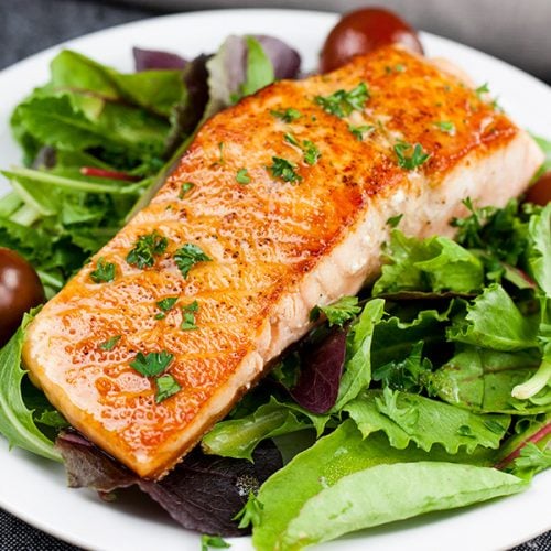 Pan-Seared Salmon Salad with Lemon Dijon Vinaigrette on a white plate.