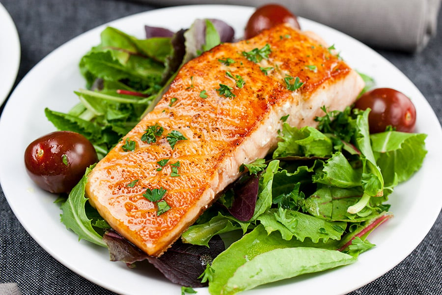 Pan-Seared Salmon Salad with Lemon Dijon Vinaigrette on a white plate.