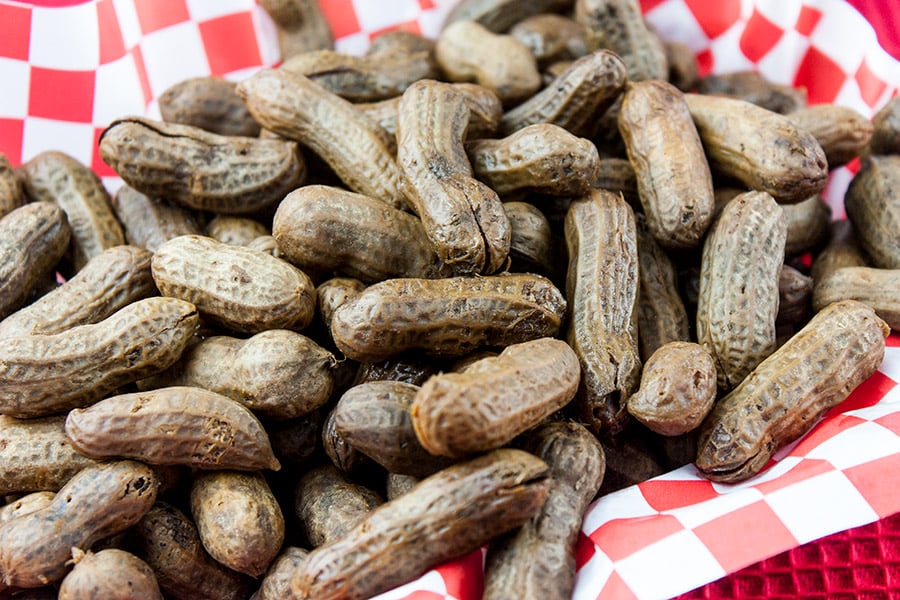 Boiled peanuts in a red basket lined with red and white checkered paper.