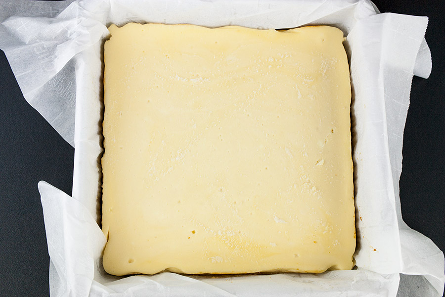 Chocolate Covered Cheesecake Bites - baked cheesecake in a parchment paper lined baking pan