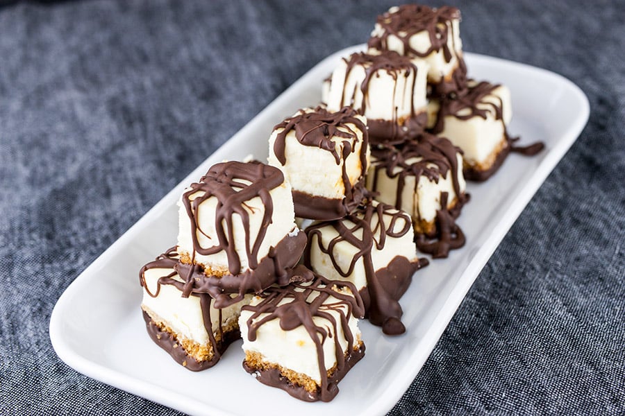 Chocolate Covered Cheesecake Bites - cheesecake bites staked on a white platter