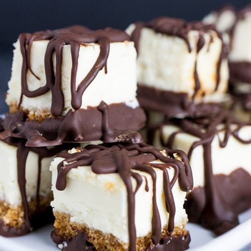 Chocolate Covered Cheesecake Bites stacked on a white plate.
