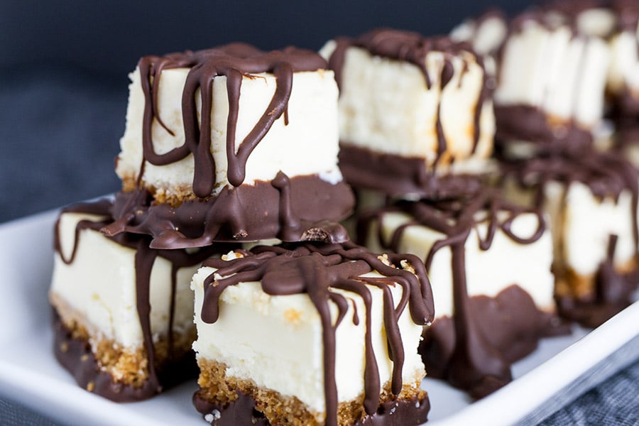 Chocolate Covered Cheesecake Bites stacked on a white plate.