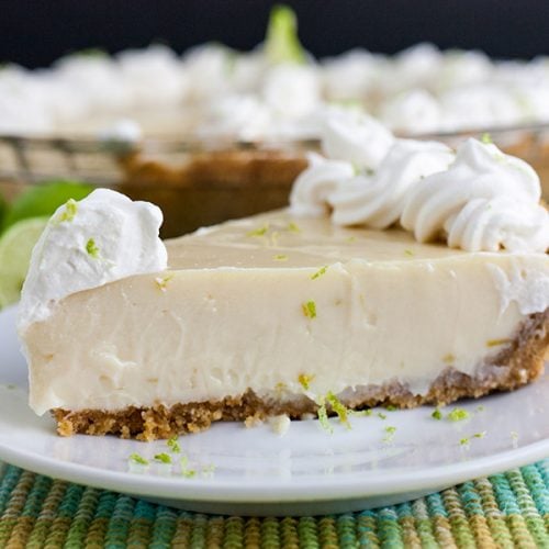 Key Lime Pie on a light plate garnished with whipped cream and lime zest.