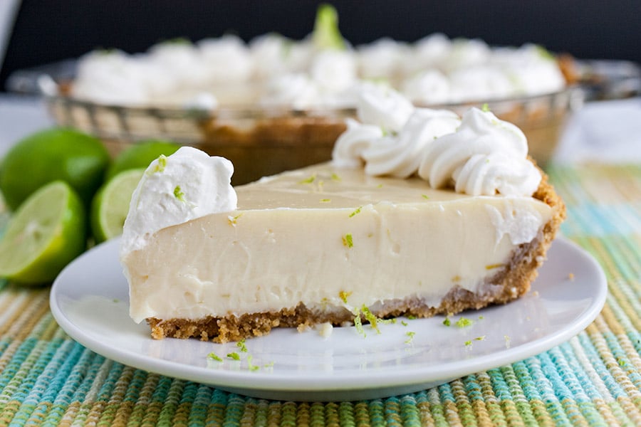 Key Lime Pie on a light plate garnished with whipped cream and lime zest.