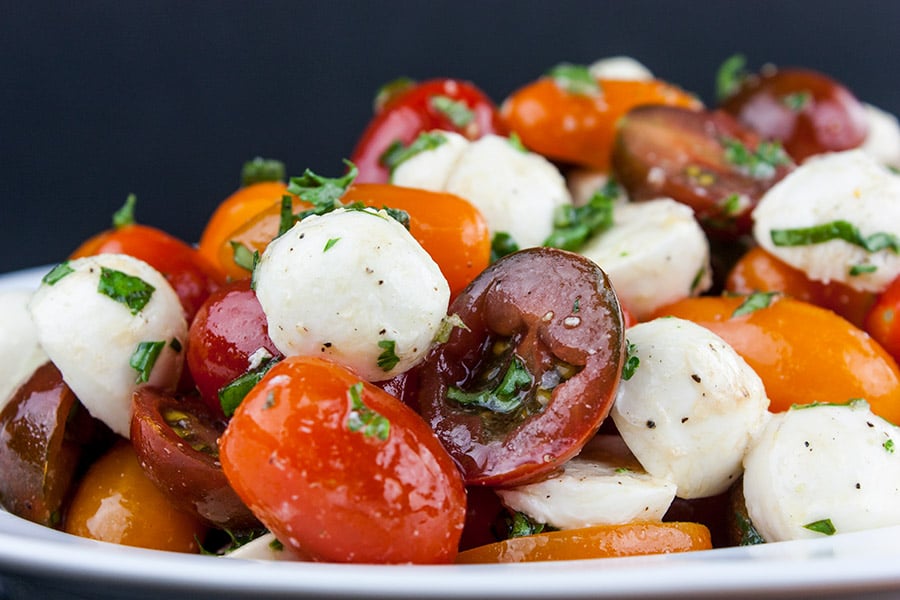 Close up of the tomato mozzarella salad in a white bowl.