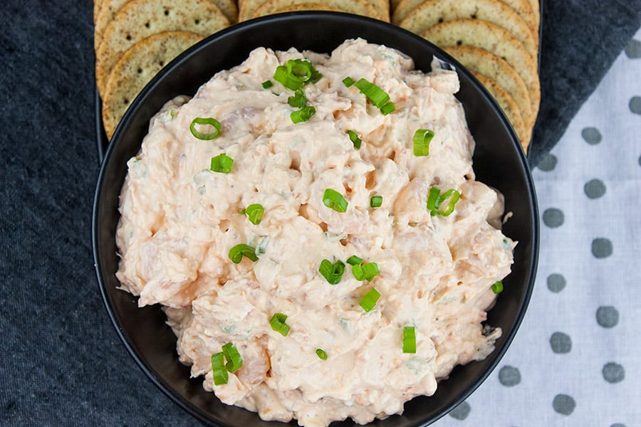 Easy Cold Shrimp Dip - in a black bowl garnished with green onions and crackers