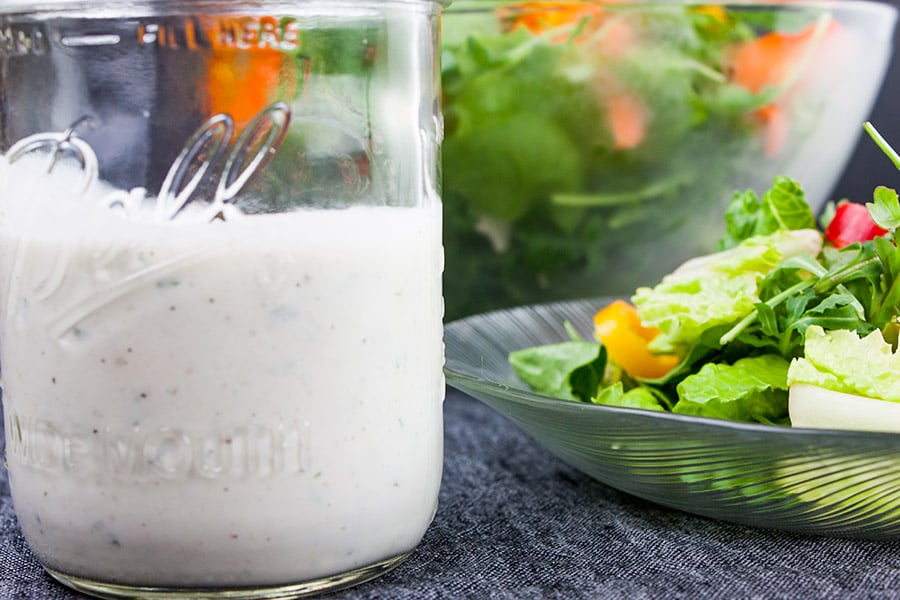 Southern buttermilk dressing in a mason jar with a salad in the background.