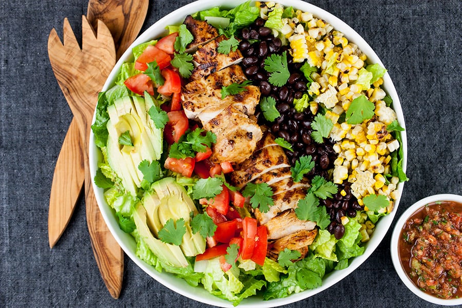 Southwest Grilled Chicken Salad - A fresh, healthy flavorful salad. Chicken marinated in a smoky adobo flavored marinade gives it more than just a "taco" flavor. Grilling the corn and jalapenos adds extra smoky flavor to this dish. Southwest Grilled Chicken Salad in a large white bowl.